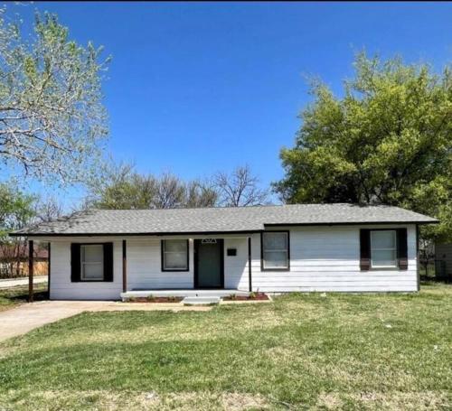 una pequeña casa blanca con un patio de césped en Serene 4 BR Home Near Weatherford-19 Minute Drive, en Mineral Wells