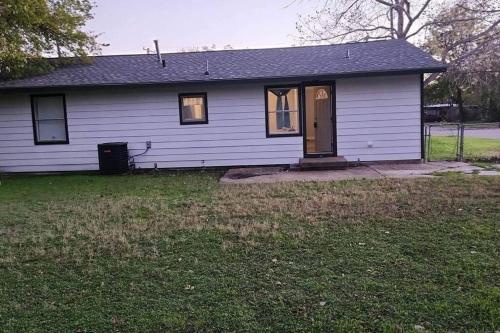 a white house with a door and a grass yard at Serene 4 BR Home Near Weatherford-19 Minute Drive in Mineral Wells