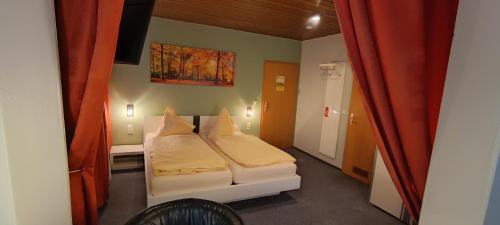 a small room with a bed and a red curtain at Hotel Romäus in Villingen-Schwenningen