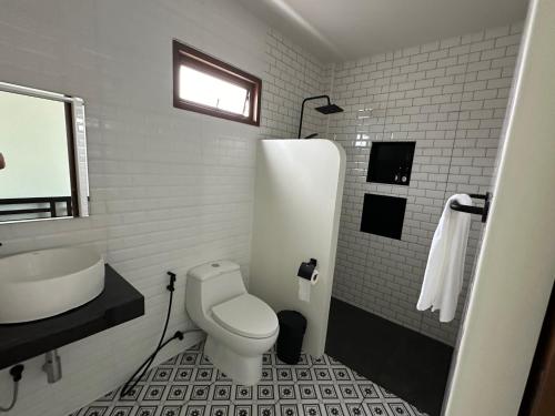 a white bathroom with a toilet and a sink at Chansi Beachresort in Tha Sala