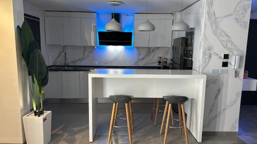 a white kitchen with a white counter and stools at Appartement La Croisette in Nabeul