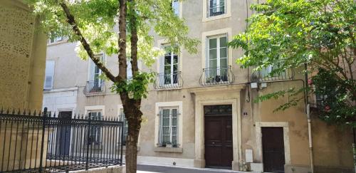 ein Apartmenthaus mit einem Baum vor einem Zaun in der Unterkunft Chambre de charme au coeur du vieux Valence - Confort & Calme in Valence