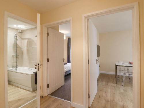 a bathroom with a bath tub and a bedroom at 21C Saville Road in Walton-on-the-Naze