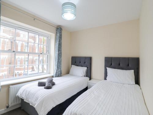 a bedroom with two beds and a window at 21C Saville Road in Walton-on-the-Naze