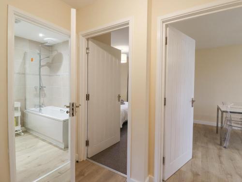 a bathroom with a bath tub and a bedroom at 21B Saville Road in Walton-on-the-Naze