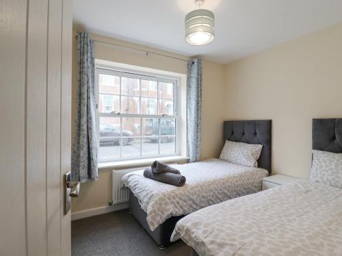 a bedroom with two beds and a window at 21A Saville Road in Walton-on-the-Naze
