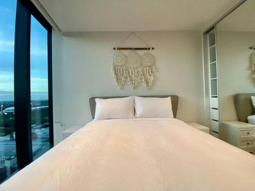 een slaapkamer met een groot wit bed en een kroonluchter bij Peaceful & Relaxing City Escape @ Rundle Mall in Adelaide
