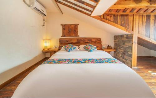 a bedroom with a large white bed in a attic at Tea House in Zhangjiajie