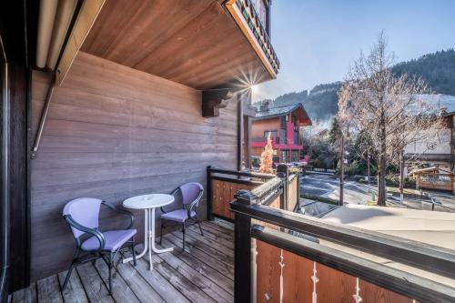 a wooden balcony with a table and chairs on it at Hotel Le Samoyede in Morzine