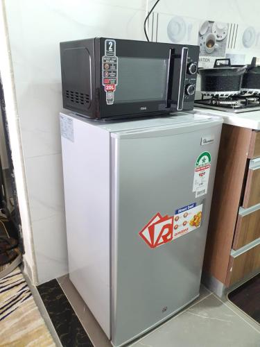 a microwave sitting on top of a refrigerator at Khomes cosy studio in Nairobi