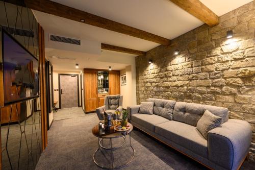 a living room with a couch and a stone wall at Grand Hotel Therme in Banya