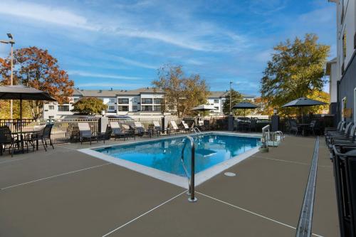 a swimming pool with chairs and umbrellas on a building at Fairfield by Marriott Chesapeake in Chesapeake