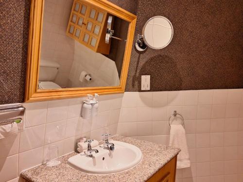 a bathroom with a sink and a mirror at Washington Central Hotel and Sleepwell Inn in Workington