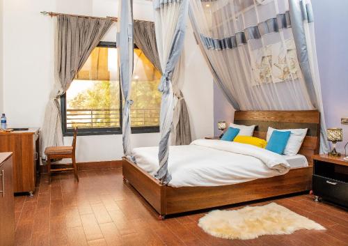 1 dormitorio con cama con dosel y ventana en Hotel Hibiscus en Buyumbura