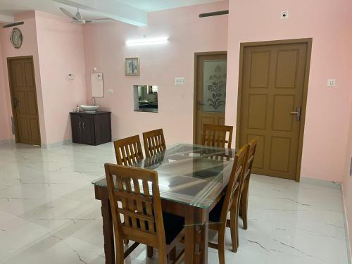 a dining room with a glass table and wooden chairs at Raha homes in Trivandrum