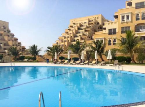 a large swimming pool in front of a building at Luxurious Private Beach & Pool, fully Furnished 1BR Apartment at Marjan Island Ras al khaimah in Ras al Khaimah