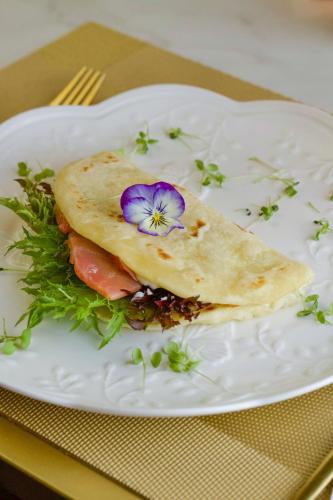 a white plate with a sandwich with a flower on it at Blumen Hotel Boutique in Canela
