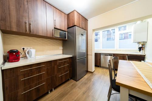 cocina con armarios de madera, mesa y nevera en L&H Apartment, en Odorheiu Secuiesc