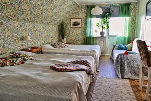 two beds in a room with green wallpaper at Bed and books på Österlens Gästhärbärge in Glemminge