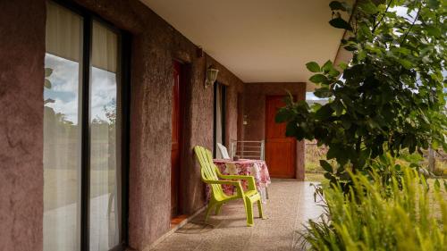 安加羅阿的住宿－卡瓦尼亞斯外拉旅館，绿椅,坐在门廊上,配有桌子