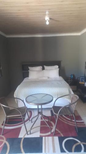 Schlafzimmer mit einem Bett mit 2 Stühlen und einem Tisch in der Unterkunft Garden Street Apartments in Alice