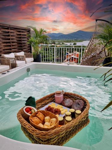 een mand met brood en eten in een zwembad bij Villa Verde Bangalô - Garopaba - SC in Garopaba