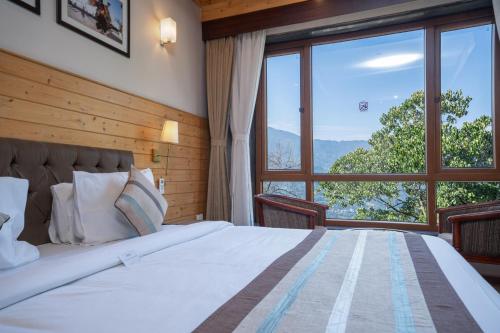 a bedroom with a large bed with a large window at Summit Alpine Abode Hotel Centrally Air Conditioned in Gangtok