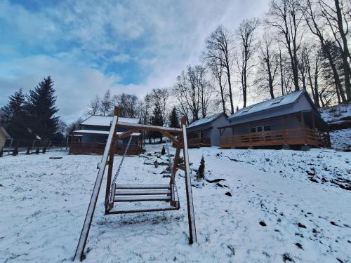a playground in the snow in front of a cabin at Domki przy Skarpie in Lądek-Zdrój