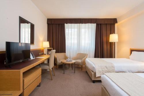 a hotel room with two beds and a desk with a television at Plaza Caserta in Caserta