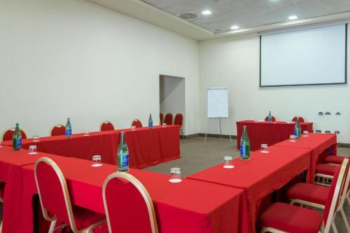 a conference room with red tables and chairs and a screen at Plaza Caserta in Caserta