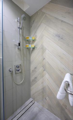 a bathroom with a shower and wooden floors at Ramada Encore Doha by Wyndham in Doha