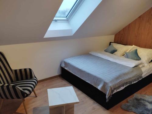 um quarto com uma cama, uma cadeira e uma janela em Apartament Brązowy 12/1 em Starogard Gdański