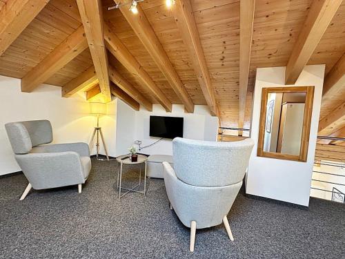 a living room with two chairs and a tv at Maisonette - 45m2 zum Relaxen, mit Garage - ME17-B in Pontresina