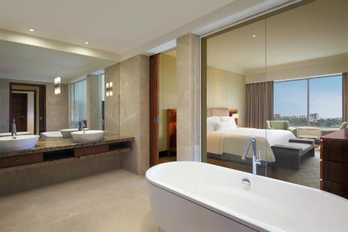 a bathroom with two sinks and a bed and a tub at The Westin Pune Koregaon Park in Pune