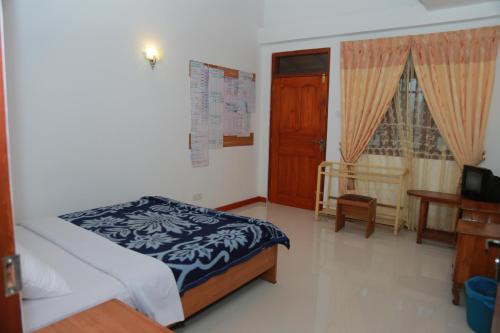 a bedroom with a bed and a television in it at Oviya Guest in Nuwara Eliya