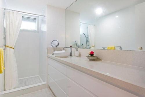 a white bathroom with a sink and a mirror at Cairns Ocean View Apartment in Aquarius in Cairns