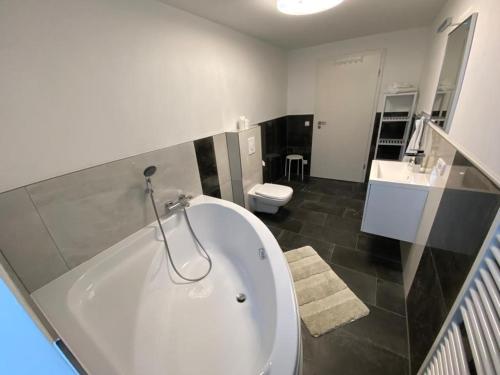 baño con bañera blanca grande y aseo en ROYAL OCEAN Ferienhaus mit Sauna, Spielekonsole und Whirlpool en Rostock