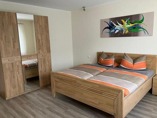 um quarto com uma grande cama de madeira com almofadas laranja em Ferienwohnung Korneli em Grenderich