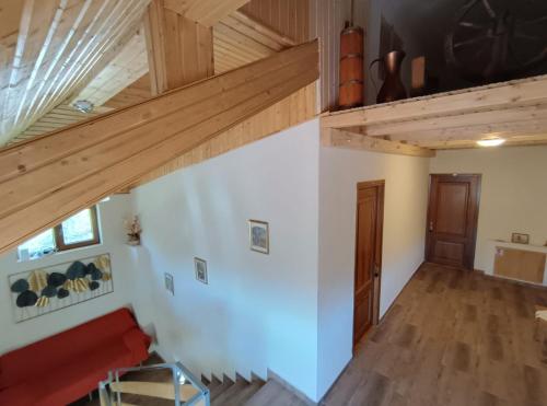 Elle comprend un salon doté de plafonds en bois et d'un canapé rouge. dans l'établissement Poiana Sașilor - Valea Doftanei, à Trăisteni