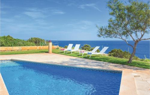 een zwembad met ligstoelen en de oceaan bij Amazing Home In Porto Colom With House Sea View in Portocolom