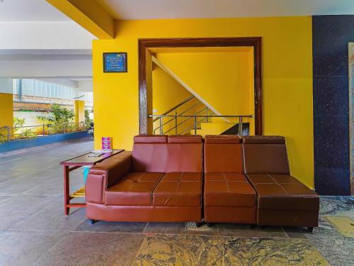 a couch sitting in a room with a yellow wall at OYO Flagship Jayam Residency in Tirupati