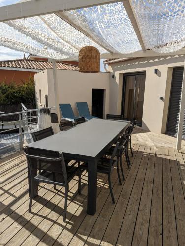 une table et des chaises sur une terrasse en bois dans l'établissement Villa de standing, plages a 25 min, golf a 5 min, à Juvignac