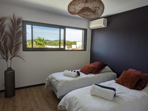 deux lits dans une chambre avec une fenêtre dans l'établissement Villa de standing, plages a 25 min, golf a 5 min, à Juvignac