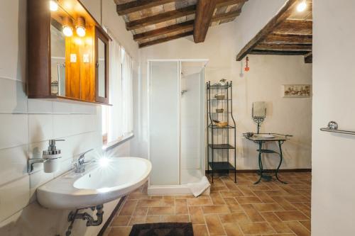 La salle de bains est pourvue d'un lavabo blanc et d'une douche. dans l'établissement A Palazzo, à Pergola