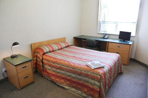 a bedroom with a bed and a desk and a bed sidx sidx sidx at Residence & Conference Centre- Barrie in Barrie