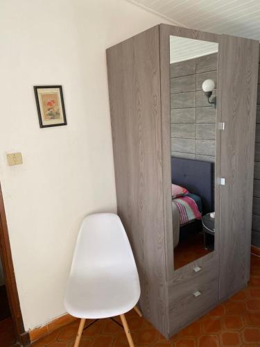 una sedia bianca e uno specchio in una stanza di Chambre au cœur des vignes a Pertuis