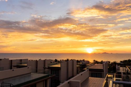 puesta de sol sobre el océano desde el balcón de un edificio en Mysterio Pool Villas - Wyndham Garden Resort en Cam Ranh