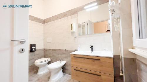 a white bathroom with a toilet and a sink at Appartamento Tramontana in Lido di Ostia