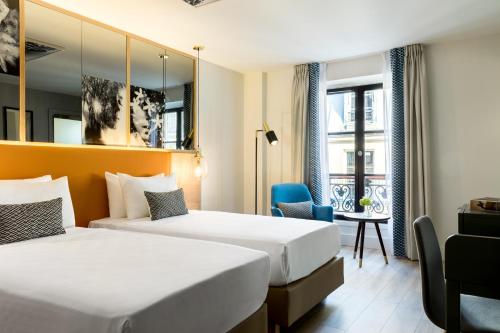 パリにあるルネサンス パリ ヴァンドーム ホテルのベッド2台とデスクが備わるホテルルームです。