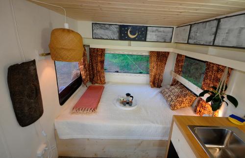 a small bedroom in a tiny house with a sink at Monte dos Vagabundos - Animal Sanctuary - Caravan nest in São Teotónio